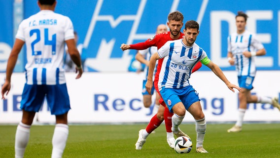 Rostocks Marco Schuster (r.) und Essens Torben Müsel kämpfen um den Ball. © IMAGO / Markus Endberg 