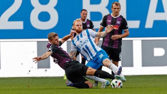 Rostocks Nils Fröling (m.) im Zweikampf mit Osnabrücks Timo Beermann © Imago Images 