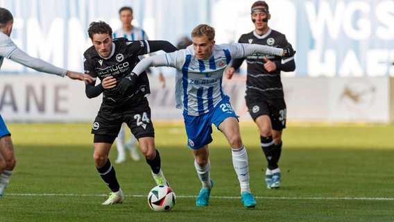 Rostocks Felix Ruschke (m.) im Zweikampf mit Bielefelds Christopher Lannert © Imago Images 