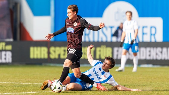 Rostocks Benno Dietze (r.) und Kölns Jonah Sticker kämpfen um den Ball. © IMAGO / Andy Bünning 