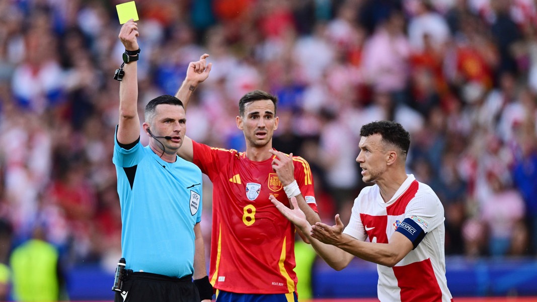 Schiedsrichter Michael Oliver (England) zeigt die Gelbe Karte, Fabian Ruiz (Spanien) und Ivan Perisic (Kroatien) sind entsetzt.