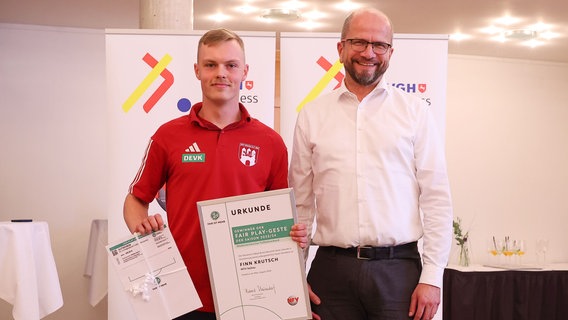 Finn Krutsch hält eine Urkunde für seine Fairplay-Geste in der Hand. Daneben steht NFV-Vizepräsidenten Jens Grützmacher. © Niedersächsischer Fußballverband Foto: Zwing