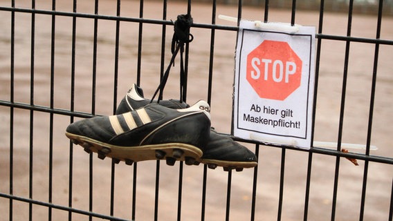 Fußballschuhe hängen an einem Zaun. © imago images / Hanno Bode Foto: Hanno Bode