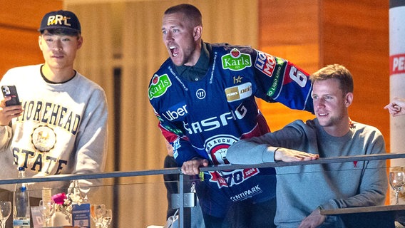 Kapitän Lewis Holtby (M.) von Holstein Kiel mit einem Trikot der Eisbären Berlin bei einem Spiel des Eishockey-Clubs © IMAGO / Matthias Koch 