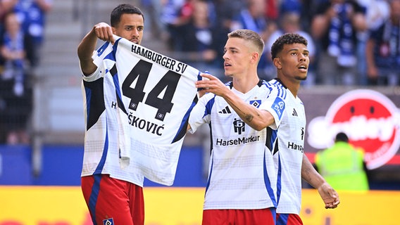 Robert Glatzel und Miro Muheim vom Hamburger SV halten nach dem Tor von Glatzel zum 1:0 gegen Münster ein Trikot von Mario Vuskovic in die Höhe © picture alliance/dpa | Gregor Fischer 