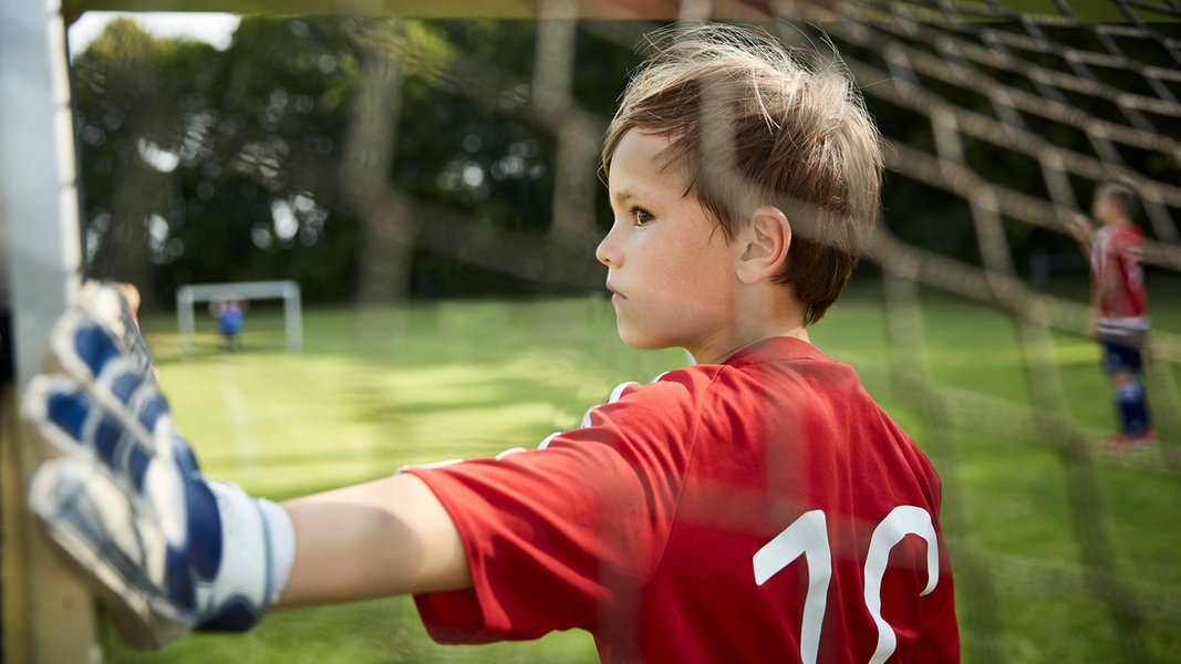 Ein kleiner Junge steht in einem Mini-Fußballtor 