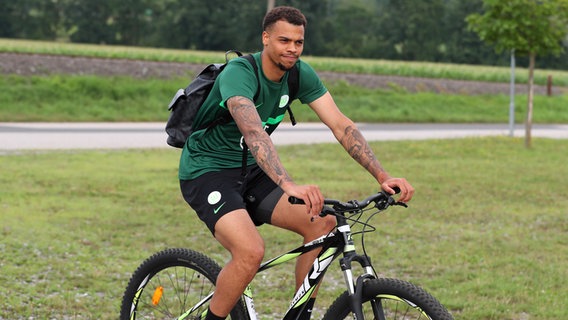 Wolfsburg-Profi Lukas Nmecha auf einem Fahrrad. © IMAGO / regios24 