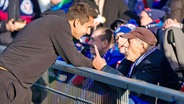 Trainer Marcel Rapp (l.) von Holstein Kiel im Gespräch mit einem Fan der KSV © picture alliance/dpa | Frank Molter 