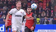 Verteidiger Hauke Wahl (l.) vom FC St. Pauli im Duell mit Bayer Leverkusen in Aktion © IMAGO / Jan Huebner 