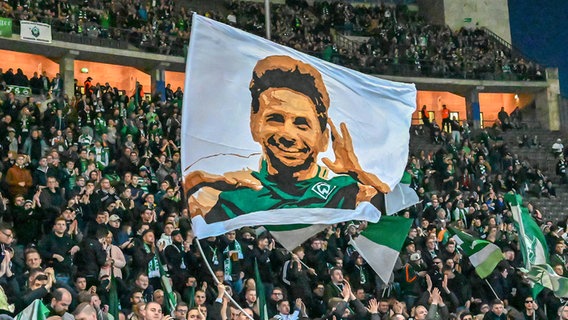 Werder-Fans mit einer Fahne, auf der Claudio Pizarro abgebildet ist © imago/Nordphoto 