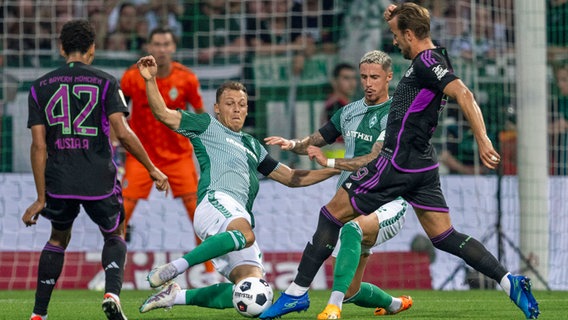 Werder Bremens Senne Lynen (2.v.l.) und Marco Friedl (2.v.r.) versuchen, Münchens Harry Kane (r.) vom Ball zu trennen. © IMAGO / Kirchner-Media 