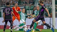 Werder Bremens Senne Lynen (2.v.l.) und Marco Friedl (2.v.r.) versuchen, Münchens Harry Kane (r.) vom Ball zu trennen. © IMAGO / Kirchner-Media 