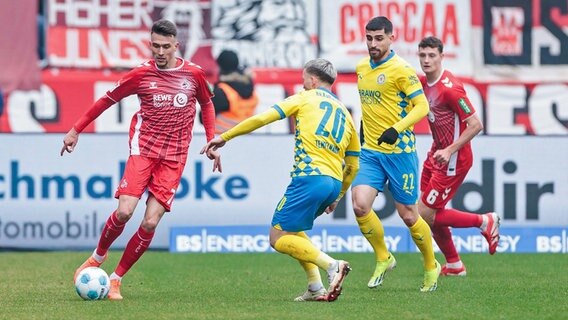 Braunschweigs Lino Tempelmann (m.) im Zweikampf mit Kölns Dejan Ljubicic © Imago Images Foto: BEAUTIFUL SPORTS Wunderl