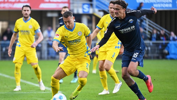 Braunschweigs Sven Köhler (l.) und Paderborns Luis Engelns kämpfen um den Ball. © IMAGO / Ulrich Hufnagel 