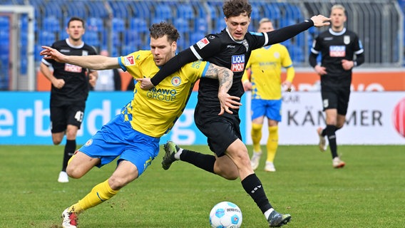 Braunschweigs Kevin Ehlers (l.) und Ulms Maurice Krattenmacher kämpfen um den Ball. © picture alliance/dpa | Swen Pförtner 