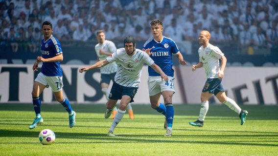 Rostocks Damian Roßbach (m.) im Zweikampf mit Schalkes Keke Topp © Imago Images Foto: xBEAUTIFULxSPORTS/Erlhofx