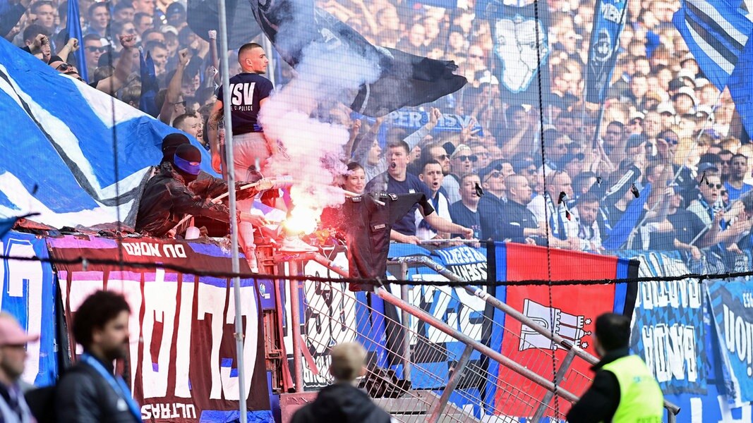 HSV-Fans zeigen ein Textil mit dem Schriftzug Polizei und brennen einen Bengalo ab.