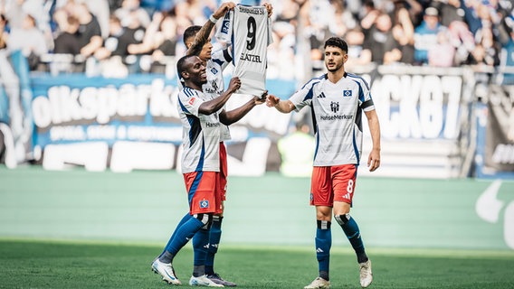 Die HSV-Spieler Jean-Luc Dompé, Davie Selke und Daniel Elfadli (v.l.) präsentieren nach einem Treffer ein Trikot vom verletzen Robert Glatzel in die Höhe. © IMAGO / Justus Stegemann 