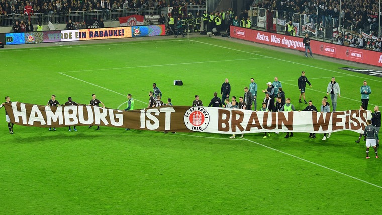 St. Paulis Spieler tragen ein Banner mit der Aufschrift "Hamburg ist braun weiß" durchs Stadion. © Witters Foto: TimGroothuis