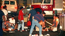 Helfer bemühen sich um die am Boden liegenden Opfer einer schweren Explosion im Zentrum der Olympia-Stadt Atlanta. © picture-alliance / dpa