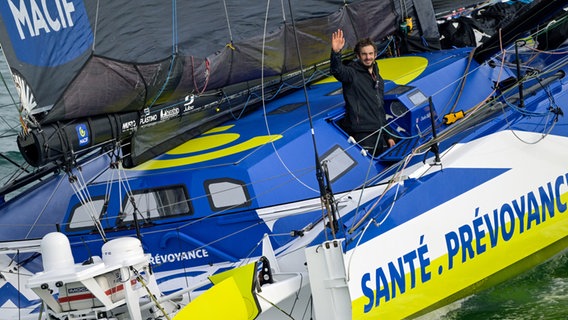 Charlie Dalin winkt kurz vor der bretonischen Küste von seiner Yacht Macif Santé Prévoyance. © Vendée Globe / Olivier Blanchet / Alea 