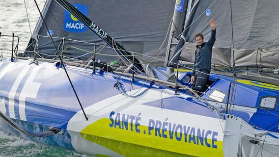 Charlie Dalin winkt kurz vor der bretonischen Küste von seiner Yacht Macif Santé Prévoyance. © Vendée Globe / Olivier Blanchet / Alea 