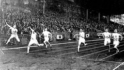 Das Finish im 200-m-Lauf der Männer bei den Olympischen Spielen in Paris: USA-Sprinter Jackson Scholz (2.v.l) wirft sich als erster in die Zielschnur. © picture-alliance/ dpa