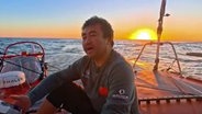 Segler Jingku Xu sitzt singend auf seinem Boot.- © vendee globe 