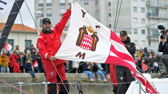 Boris Herrmann auf seiner Malizia in Les Sables-d'Olonne mit der Flagge des Yacht Club de Monaco © Olivier Blanchet / Alea 