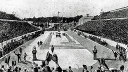 Der griechische Bauernsohn Spyridon Louis wird auf den letzten Metern im Marmorstadion von Athen von Kronprinz Konstantin und Prinz Georg begleitet, während die Zuschauer im vollbesetzten Stadion jubeln und die Hüte schwenken. © ullstein bild - ullstein bild 