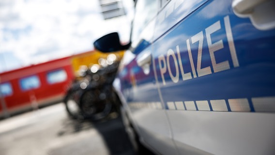 Ein Polizeiauto steht am Bahnhof, im Hintergrund ein roter Zug. © picture alliance / dpa | Matthias Balk 