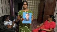 eine Frau in Sri Lanka hält das Bild ihres vermissten Ehemanns hoch © NDR Foto: Charlotte Horn