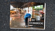 Unter der Hamburger Sternbrücke schützt sich eine Person mit einer blauen Ikea Tasche vor dem Regen. © Junius Verlag Foto: Junius Verlag