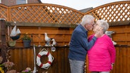 Eine Frau und ein Mann stehen vor einem Gartenzaun und küssen sich. © NDR/Magdalena Maria Stengel 