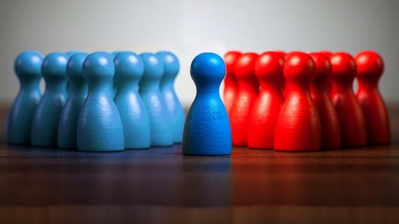 Zwei Gruppen Spielfiguren stehen sich gegenüber, eine Figur steht im Zentrum. © photocase Foto: MichaelJBerlin