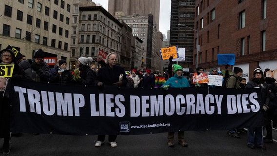 Demonstranten in New York tragen ein Banner mit der Aufschrift "Trump lies democracy dies" durch eine Straße. © Imago / ZUMA Press Wire Foto: Gina. M. Randazzo