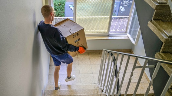 Ein Mann trägt bei einem Umzug einen Karton durch ein Treppenhaus. © picture alliance / Schoening Foto: Schoening