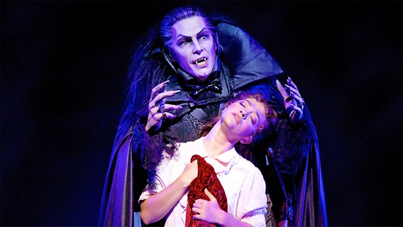 In einer Szene aus dem Musical "Tanz der Vampire" hält Graf von Krolock die Wirtstochter Sarah umklammert. © Stage Entertainment 