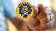 Early In-Person Voting Starts In Virginia, eine Hand hält einen Aufkleber mit der Aufschrift: Presidential Election I Voted 2024 © AFP Foto: ANDREW HARNIK