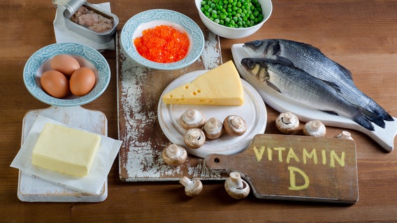 Butter, Eier, Fisch, Erbsen, Käse, Champignons, Fisch in der Dose, orangefarbene Kügelchen auf einem Teller und ein Holzbrett auf dem Vitamin D steht. © fotolia.com Foto: bit24