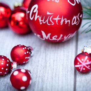 Rote Christbaumkugeln und Zimtstangen liegen auf einem weißen Holztisch. © Colourbox Foto: JuNiArt