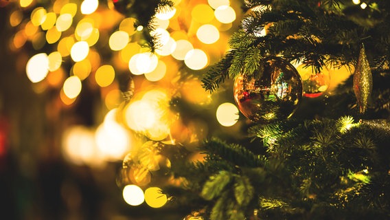 Ein geschmückter Weihnachtsbaum mit goldenen Lichtern im Hintergrund © photocase Foto: David W