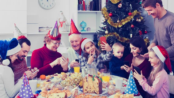 Familienmitglieder hantieren mit ihren Smartphones am gedeckten Weihnachtstisch herum. © fotolia Foto: SJackF