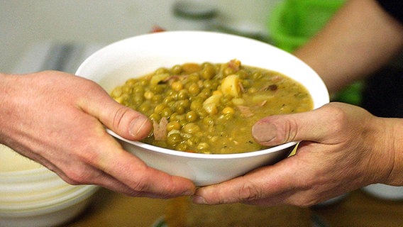 Ein Teller Suppe wird überreicht. © picture-alliance / ZB Foto: Jens Kalaene