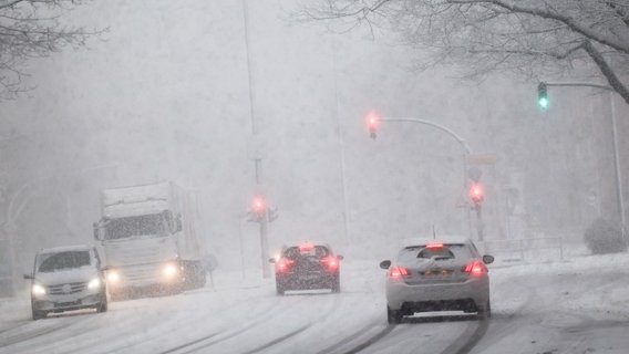 Fahrzeuge sind bei Schneefall auf einer Straße in Hamburg unterwegs. © Christian Charisius/dpa Foto: Christian Charisius