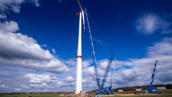 Mit einem Spezialkran wird der vormontierte Propeller an das Maschinenhaus einer Windkraftanlage gehoben. Der Windpark Hoort südlich von Schwerin wird in den nächsten Wochen fertig aufgebaut sein. Die 16 Windkraftanlagen der Firma Nordex werden im Auftrag der Betreiberfirma Loscon an der Autobahn A24 errichtet. Die knapp 200 Meter hohen Anlagen sollen ihren Normalbetrieb im Sommer starten und jährlich rund 120 Millionen Kilowattstunden Strom erzeugen. Damit können durchschnittlich 35.000 Haushalte versorgt werden. Der Windpark umfasst eine Fläche von circa 228 Hektar. © picture alliance/Jens Büttner Foto: Jens Büttner