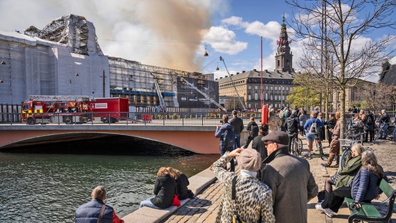 Menschen vor der durch Brand stark beschädigten Historischen Börse in Kopenhagen - es ist nur noch das Gerippe zu erkennen © Mads Claus Rasmussen/Ritzau Scanpix Foto/AP +++ dpa-Bildfunk +++ Foto: Mads Claus Rasmussen