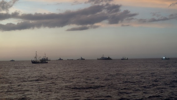 Mehrere Schiffe und Boote schwimmen in der Abenddämmerung auf dem Wasser, einige von ihnen haben Scheinwerfer angeschaltet. © Deutsche Gesellschaft zur Rettung Schiffbrüchiger (DGzRS) Foto: Deutsche Gesellschaft zur Rettung Schiffbrüchiger (DGzRS)